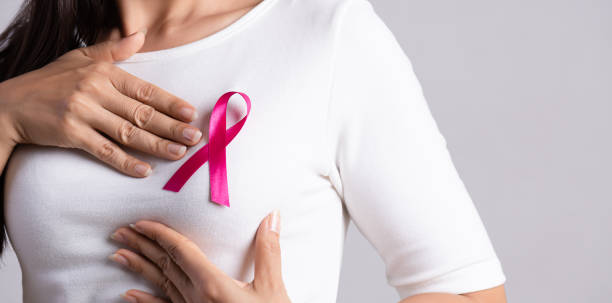 primer plano de la cinta de la insignia rosa en el pecho de la mujer para apoyar la causa del cáncer de mama. concepto de concienciación sobre la salud, la medicina y el cáncer de mama. - breast cancer fotografías e imágenes de stock