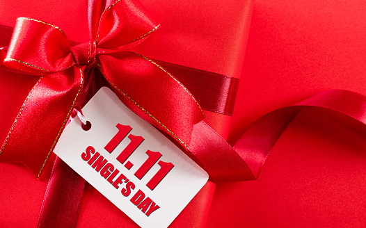 Online shopping of China, 11.11 single's day sale concept. White paper tag with text 11.11 single's day sale hanging on gift box over red background.