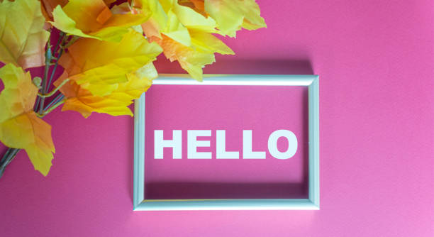 istock Hello text in silver frame and pink background, near golden foliage 1273589799