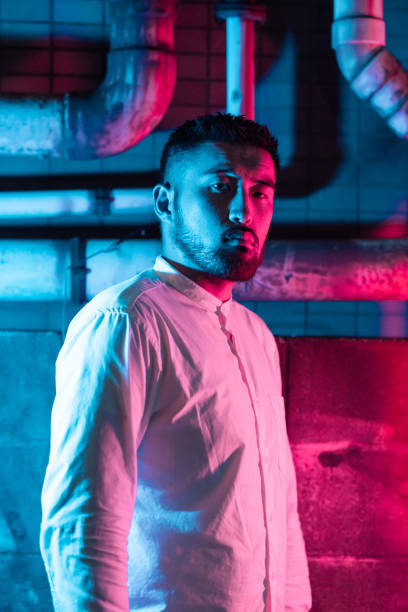 portrait of young man lit by pink and blue neon light in city - vertical bright brightly lit vibrant color imagens e fotografias de stock