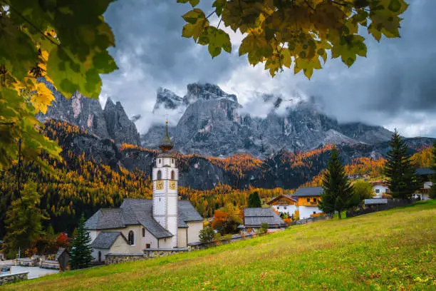 Photo of Cute alpine village with traditional mountain church, Dolomites, Colfosco, Italy