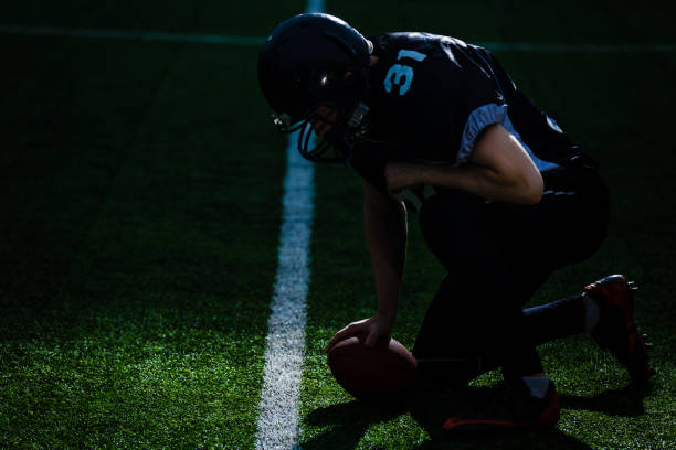istock Football Player with a red uniform on his knees, on a Stadium. 1273593204