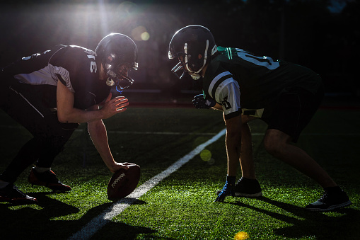 American football players are ready to start a match on modern field at night