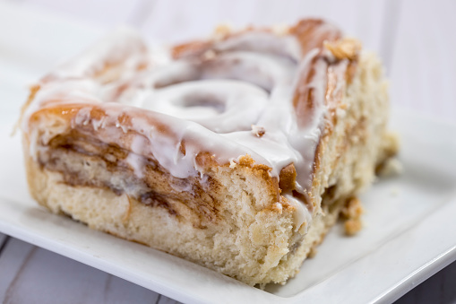 Close up of a cinnamon roll on a white plate.