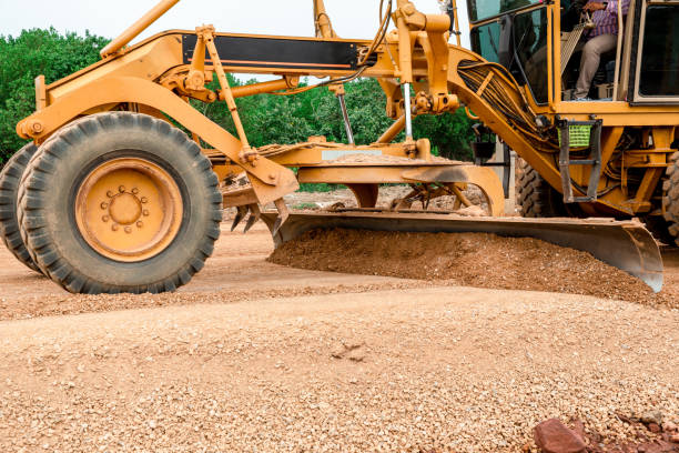 Grader Road Construction Grader industrial machine on construction of new roads. the blade of a motor grader in the process of leveling a sandy road foundation. Grader is working on road construction. grader road construction grader máquina industrial en la construcción de nuevas carreteras. la hoja de una motoniveladora en el proceso de nivelación de una base de carretera arenosa. grader está trabajando en la construcción de carreteras.