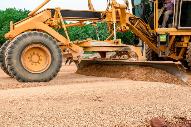 grader road construction grader macchina industriale sulla costruzione di nuove strade. la lama di un livellatore motore nel processo di livellamento di una fondazione di strada sabbiosa. grader sta lavorando alla costruzione di strade. - grading foto e immagini stock