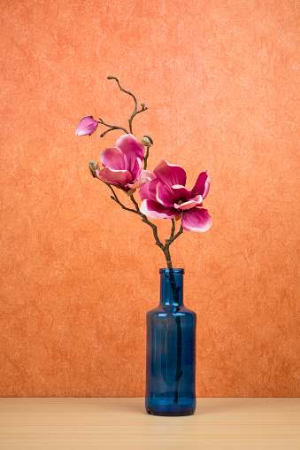 Vase with (artificial) flowers on a terracotta background