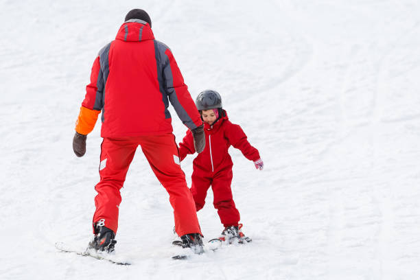 Professional ski instructor is teaching a child to ski on a sunny day on a mountain slope resort with sun and snow. Family and children active vacation. Professional ski instructor is teaching a child to ski on a sunny day on a mountain slope resort with sun and snow. Family and children active vacation. ski instructor stock pictures, royalty-free photos & images