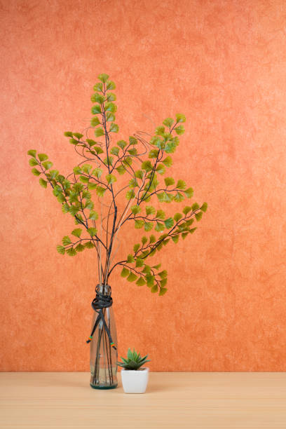 istock Glass vase with (artificial) flowers on a terracotta background 1273605269