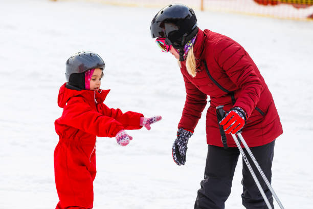 istock Professional ski instructor is teaching a child to ski on a sunny day on a mountain slope resort with sun and snow. Family and children active vacation. 1273605275