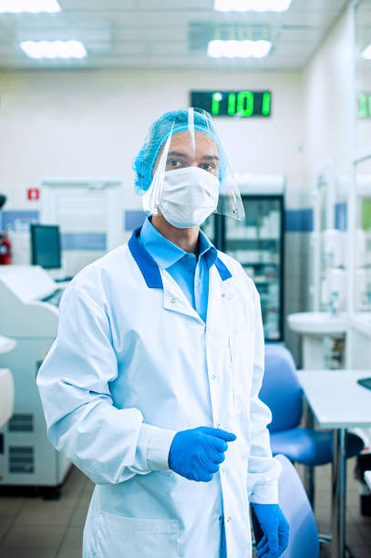 istock A medical worker, a laboratory assistant in a protective mask, visor, disposable cap and rubber gloves stands in a laboratory, hospital. 1273606206