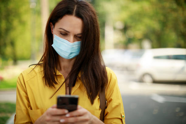 istock Woman with face protective mask using mobile phone outdoor 1273608293