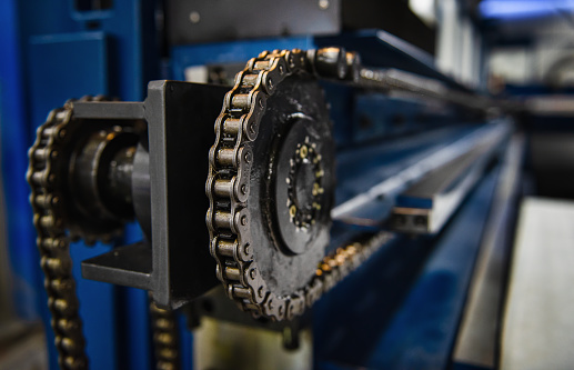 Close up of lubricated driving chain on a production machine