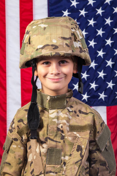アメリカ国旗を持つ兵士のような服を着た少年 - child military saluting flag ストックフォトと画像