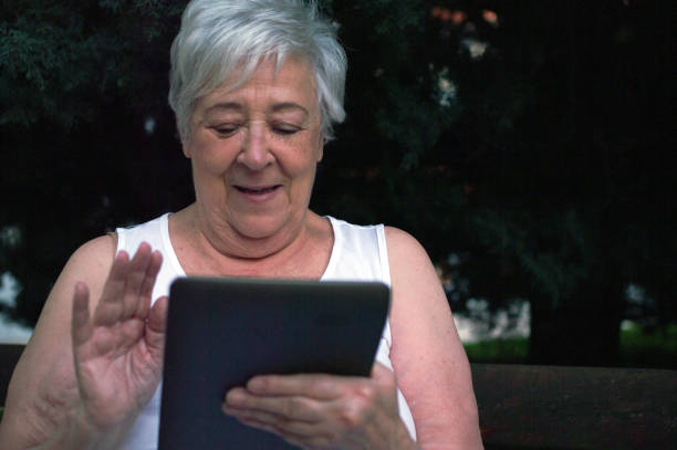 istock Elderly woman studying, communicating with a tablet from a public park 1273616956