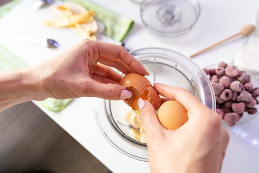 Cracking egg into blender to mix it with other ingredient to make a heathy cupcakes