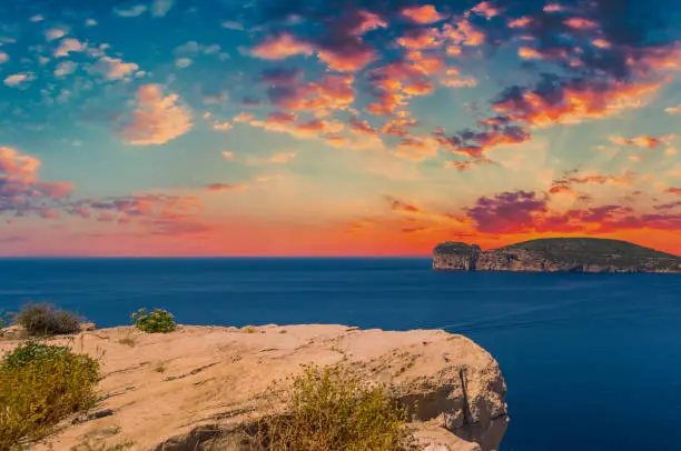 Landscape of the coast of Capo Caccia, in Sardinia, at dramatic sunset with red clouds