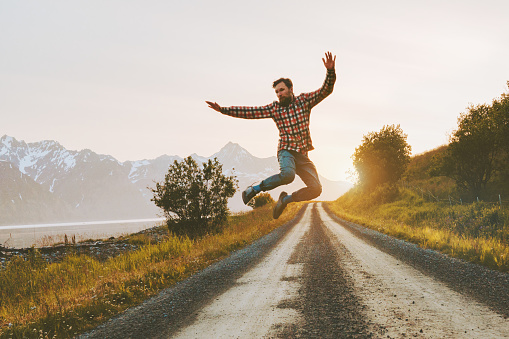 Happy farmer jumping for joy in his canola field at sunset