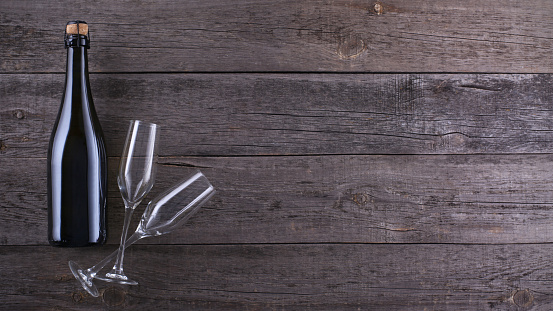 Bottle of sparkling wine and two wineglasses on old gray wooden background