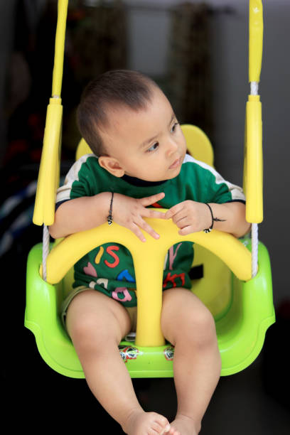 Cute baby swinging on swing at home.