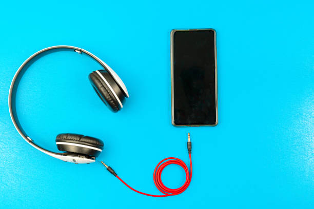 istock Modern smartphone in blue case with awesome wireless headphones on lazure textured background with copy space 1273637975