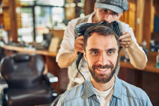 理髪店で約束をしている若いブルネットの男 - frizzy human hair hairdresser hair dryer ストックフォトと画像