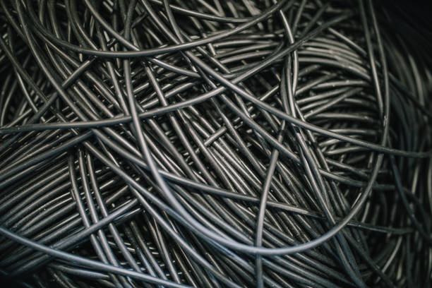 Pile of twisted old aluminum electrical high-voltage cable recyclable scrap cables. Monochrome background