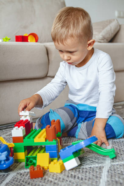 istock Child playing with toy blocks sitting on floor 1273661094