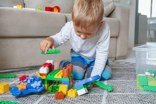 istock Child playing with toy blocks sitting on floor 1273661117