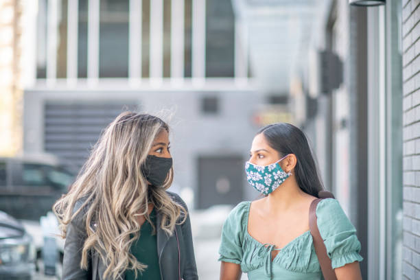 istock Female friends outside wearing protective face mask 1273664438