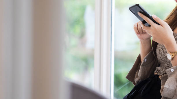 istock Young thai woman using mobile sitting at window 1273664605
