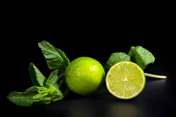 feuilles naturelles de lime et de menthe sur un fond sombre. agrumes tropicaux. - lime fruit citrus fruit portion photos et images de collection