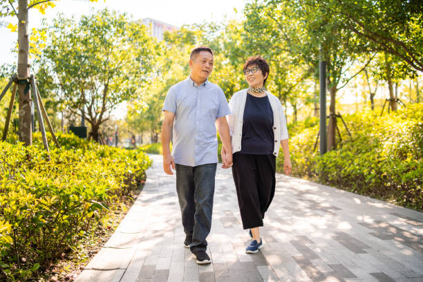 istock Senior Asian couple walking in a park 1273665724