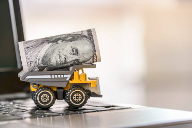 istock US USD one hundred dollar and a dump truck on a laptop computer 1273671381