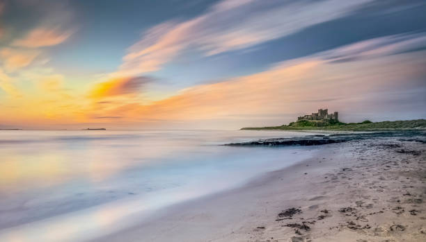 frühmorgens licht an der küste in der nähe von bamburgh castle, northumberland, uk - bamburgh stock-fotos und bilder