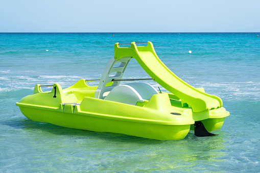 Green pedal boat on Sardinian sea in a turquoise sea. Pedalboat
