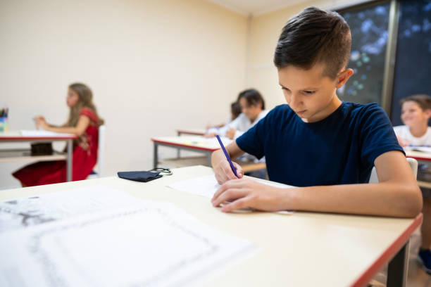 istock Young schoolboy writing in the note pad during the class 1273680161