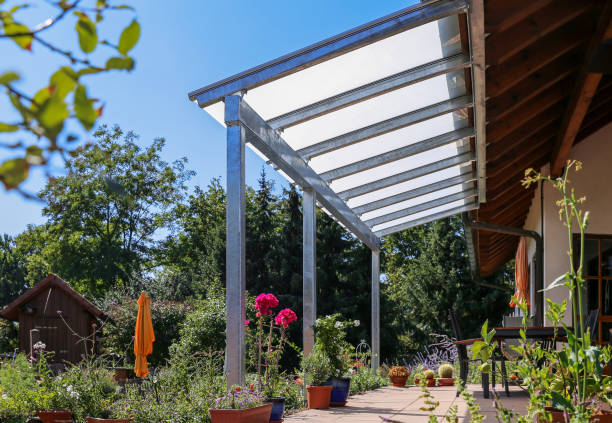 Terrace with glass roofing and a view of the garden Glass patio cover with a view of the garden. awning stock pictures, royalty-free photos & images