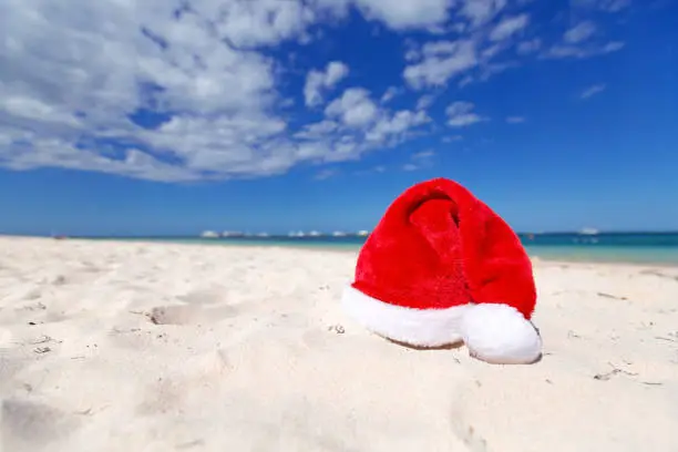 Christmas santa hat on sandy caribbean beach with sea view background