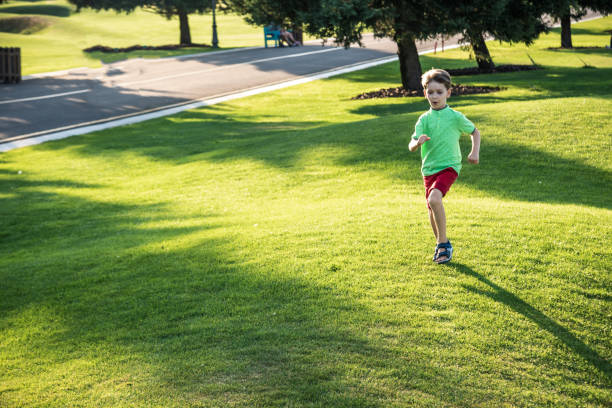 маленький мальчик работает на траве на огромном поле для гольфа - golf child sport humor стоковые фото и изображения