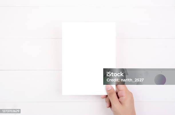 Hand Of Young Man Holding Poster Or Card Or Brochure With White Paper Blank On Wooden Table Greeting Card A5 A4 Flyer Advertising And Message For Design Empty Copy Space Mockup Template Stock Photo - Download Image Now