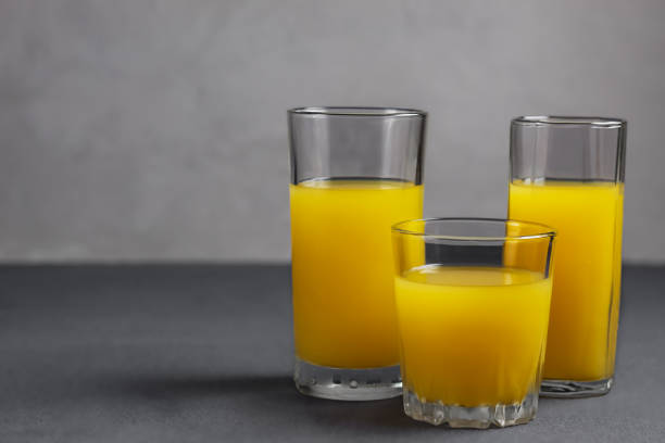 istock Orange juice in glasses on gray background 1273702785