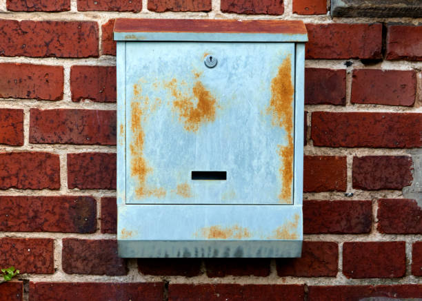 istock Uninscribed grey mailbox with rust stains on a red spotted brick wall, concept 1273704360