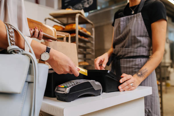 Paying with her credit card in a bakery shop, making a purchaise stock photo