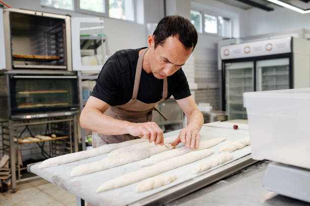 istock Keen male baker making baguettes on a flowered table in a kitchen 1273705834
