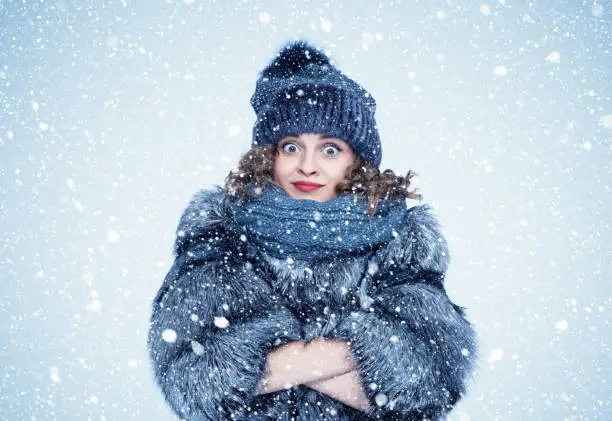 Photo of Portrait of a young pretty happy woman in a silver fox fur coat on a background of snow