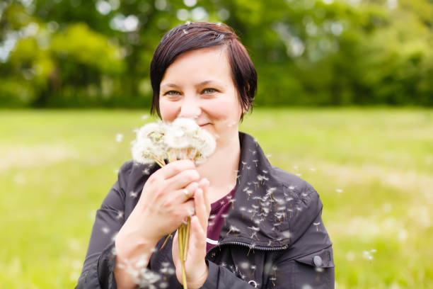 istock Girl blowing on white dandelion in the forest 1273708084