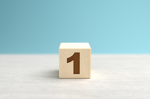 A wooden toy cube with the number 1.