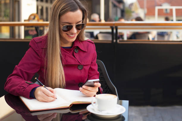 istock Happy young woman using smart phone and writing 1273711472