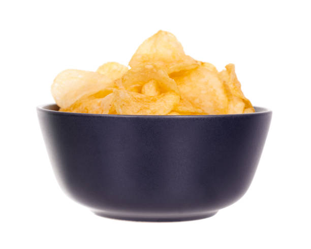 Golden potato chip in dark bowl, isolated on white background. stock photo